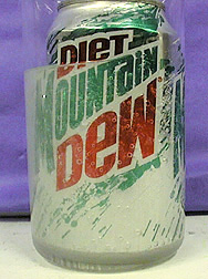 A can floats in a beaker with clear liquid and bubbles.
