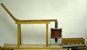 A wooden ramp with an electromagnet at the bottom of the slope and a box with wooden channels.