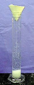 White solid forming at the bottom of a glass column with funnel containing filter paper
