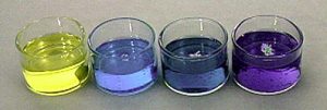 Row  of four crystallizing dishes with yellow, blue, and green liquids