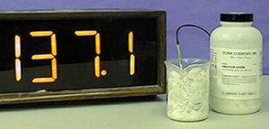 A thermometer, a probe with a cable in a cloudy mixture inside a beaker, and a capped bottle with a label