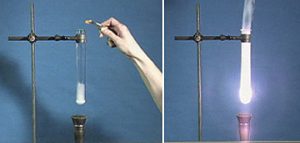 Using tweezers, a hand holds a cheeto over a test tube containing a white substance over a burner. A stand holds the tube in place. In the second photo, purple-white flames appears in the tube.