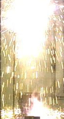 White flames and white sparks inside a protective shield over a large crucible