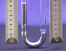 Two rulers flank a glass tube with silver metal liquid