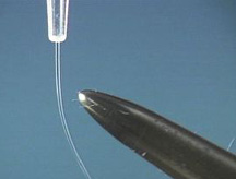 The photo shows a clear liquid repelling from a buret tip near a dark rod.