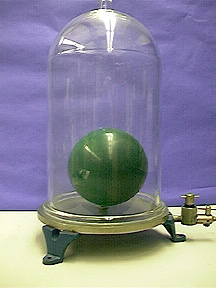 An inflated green balloon inside a glass jar with a fixture for an aspirator on a green table