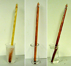 Three photos, each showing a glass tube in a container: The first photo shows a dark brown substance at the bottom of the tube, and a yellow-brown vapor in the upper portion of the tube. The tube is in ice water inside a beaker. The second tube shows dark brown substance at the bottom of the tube and brown vapor in the tube in an empty container. The third photo shows a glass tube with dark brown vapor in clear liquid inside a container.