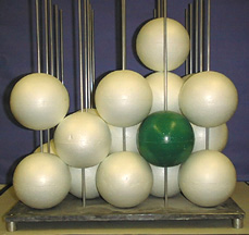 A display representing molecular models, using white spheres and one green sphere on silver sticks.