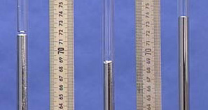 Three glass tubes each with silver liquid next to a meter stick showing measurements.