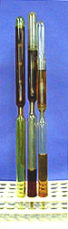 Three glass tubes each with a constriction point and brown liquid held in place by a white test tube rack.