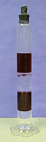 A stoppered glass column with bands of dark and clear immiscible liquids