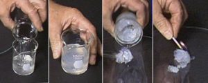 A four-photo sequence: The first photo shows a hand pouring clear liquid from a beaker into a second beaker with cloudy liquid. In the second photo, a hand holds a beaker with cloudy liquid. In the third photo, a hand tilts a beaker with gray substance, and gray substance is poured onto a dark surface. In the fourth photo, a hand holds a lit match next to the solid gray mass on the dark surface.