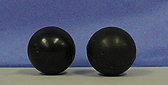 Two black balls on a gray surface against a blue background