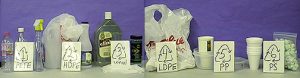 A collection of plastic items placed next to placards with recycling codes