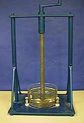 A brown liquid in a crystallizing dish winds upward along a rod of a hand cranked disc.