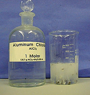 A reagent bottle next to a beaker in which gas is released by a solid in a solution.