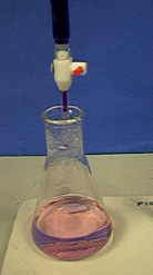 A clear and colorless liquid turns pink after addition of a purple liquid from a buret.