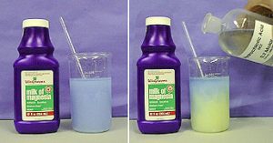 In the first photo, a capped labeled blue bottle next to a beaker with blue liquid and a stir rod. In the second photo, a capped, labeled blue bottle and the beaker with blue liquid shows yellow liquid in its lower layer. A hand pours the labeled bottle with clear liquid into the beaker.