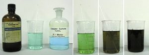In the first photo, a capped dark labeled bottle, a beaker with a clear green-blue liquid and a stir rod, and a stoppered bottle with the label "Copper Sulfate" and blue liquid. In the second photo, a beaker with clear green liquid. The third and fourth photos each shows the beaker with successive brown and black color changes to the liquid.
