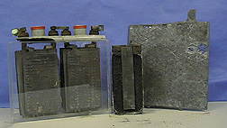 A marine battery in a plastic casing, half of a cut dry cell battery, and a lead acid battery electrode against a blue background