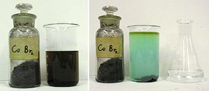 A capped, labeled bottle with a black solid and a beaker with dark liquid. In the next photo, a capped, labeled bottle with black solids, a beaker with an upper layer of dark green liquid and a layer of blue liquid. Dark solids are seen at the bottom of the beaker. A flask with clear liquid is next to the beaker.