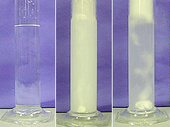 A cylinder with clear colorless liquid, a cylinder with bubbles and a white solid, and a third cylinder with bubbles, a white precipitate, and a dissolving tablet at the bottom of the cylinder.