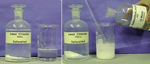 A clear liquid poured into a beaker of clear liquid forms a white solid.
