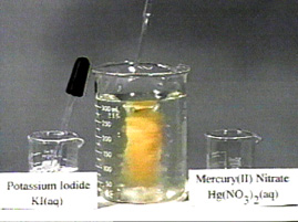 A beaker with clear liquid and an eye dropper, a larger beaker with an orange vortex and dropper, and a beaker with clear liquid