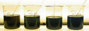 Four beakers of dark liquids with stir rods