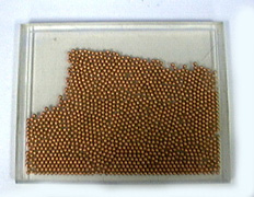 Copper colored beads in a plexiglass case