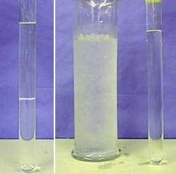 The first photo shows a column with an immiscible upper layer of clear liquid and a lower layer of slightly cloudy liquid. The second photo shows the column with no layers next to an ice bath in a large glass cylinder.