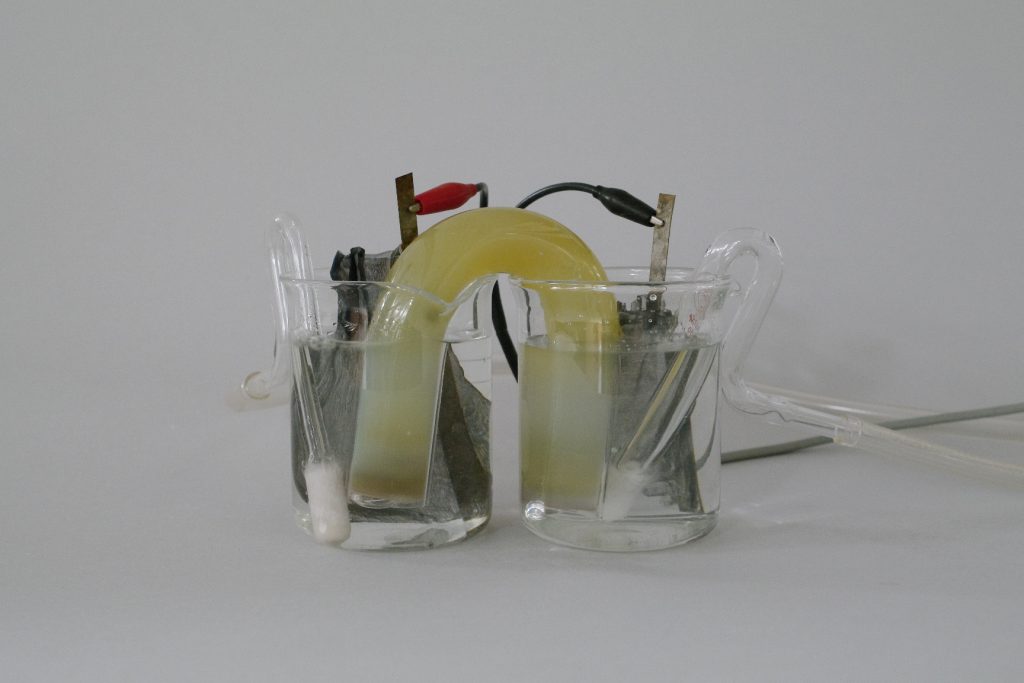 Each end of a salt bridge is placed in a beaker with clear liquid. Leads are placed on the strips of metals inside the beakers. The beakers also contain fritted glass fittings that carry gases.