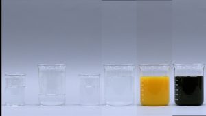 Three beakers with clear liquids, a beaker with cloudy liquid, a beaker with orange liquid, and a beaker with dark liquid