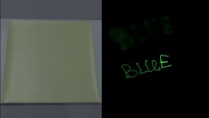 In the first photo, a pale green sheet on a gray surface. In the second photo, glowing green letters spell out the word "Blue" in a darkened room.