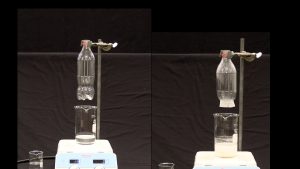 Two photos with a soda bottle clamped in place on a ring stand and held above a beaker on a hot plate. A beaker is seen next to the hot plate. The first photo shows a bottle with clear liquid and a beaker with clear liquid. A smaller beaker with liquid is seen next to the plate. The second photo shows a bottle with no bottom and a white discoloration at the bottom of the bottle. The beaker contains a cloudy white liquid and lower layer with a dissolved substance.